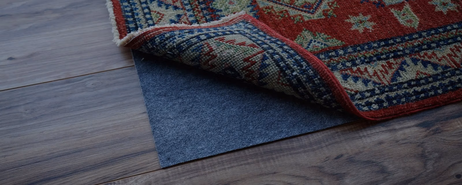 Rug pad being fitted beneath an area rug on hardwood flooring